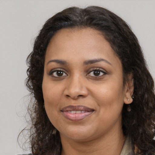 Joyful black adult female with long  brown hair and brown eyes