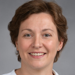 Joyful white adult female with medium  brown hair and grey eyes