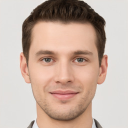 Joyful white young-adult male with short  brown hair and grey eyes