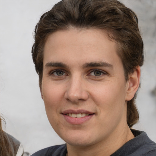 Joyful white young-adult male with short  brown hair and grey eyes