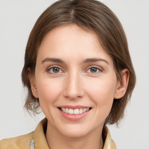 Joyful white young-adult female with medium  brown hair and grey eyes