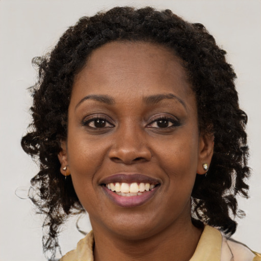 Joyful black young-adult female with long  brown hair and brown eyes
