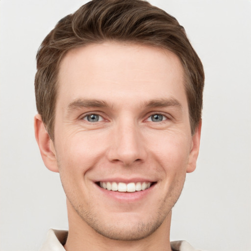 Joyful white young-adult male with short  brown hair and grey eyes