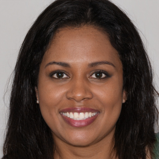 Joyful black young-adult female with long  brown hair and brown eyes