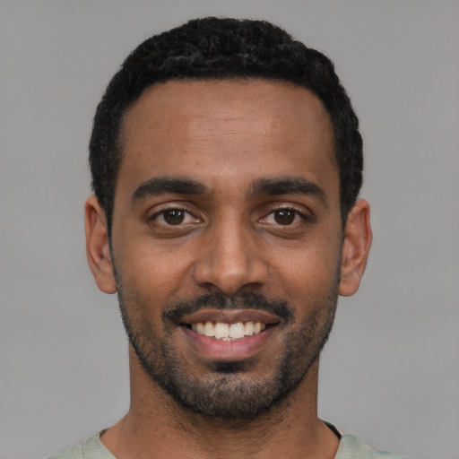 Joyful black young-adult male with short  black hair and brown eyes