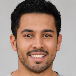 Joyful latino young-adult male with short  brown hair and brown eyes