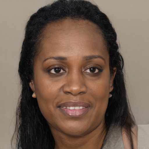 Joyful black adult female with long  brown hair and brown eyes