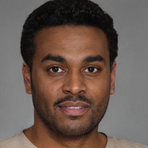 Joyful black young-adult male with short  brown hair and brown eyes