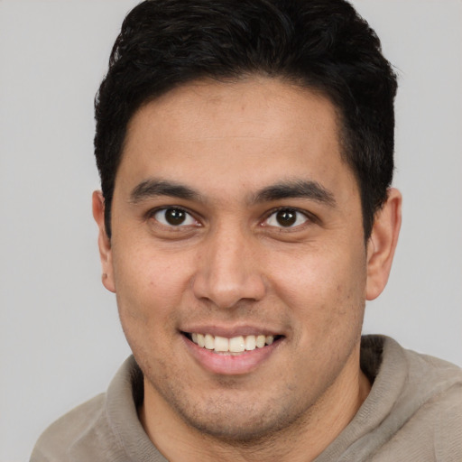 Joyful latino young-adult male with short  brown hair and brown eyes
