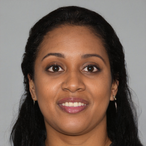 Joyful black young-adult female with long  brown hair and brown eyes