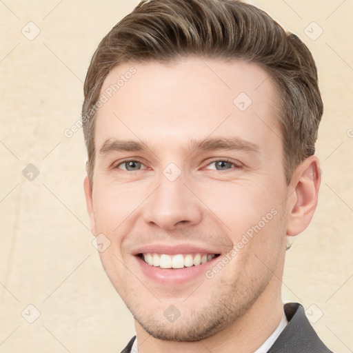 Joyful white young-adult male with short  brown hair and grey eyes