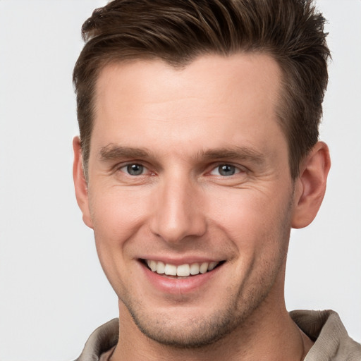 Joyful white young-adult male with short  brown hair and grey eyes