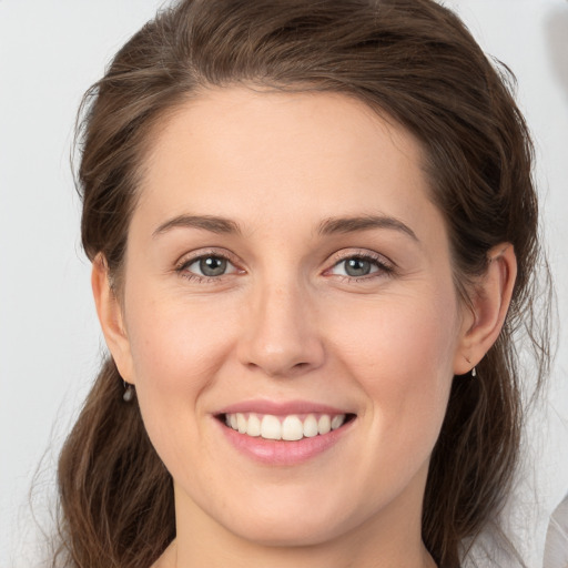 Joyful white young-adult female with medium  brown hair and grey eyes