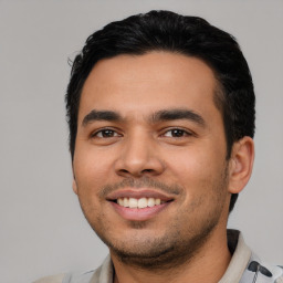 Joyful latino young-adult male with short  black hair and brown eyes