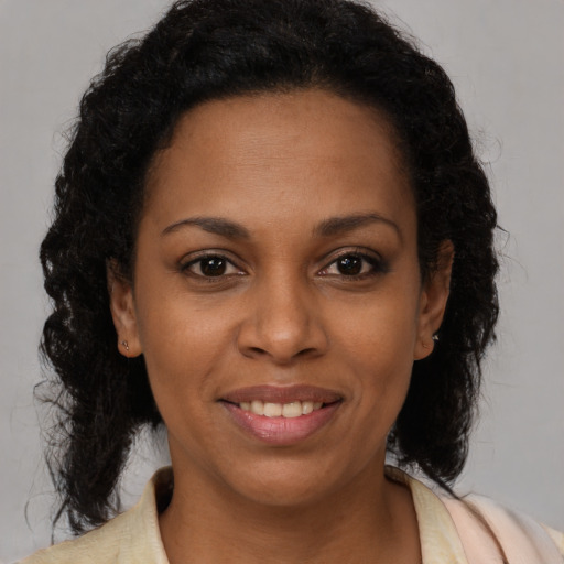 Joyful black young-adult female with long  brown hair and brown eyes