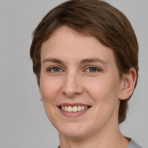 Joyful white young-adult female with short  brown hair and grey eyes