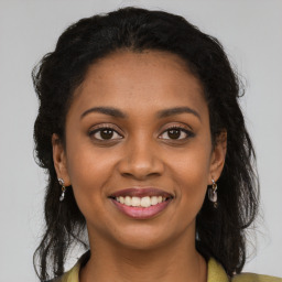 Joyful black young-adult female with long  brown hair and brown eyes