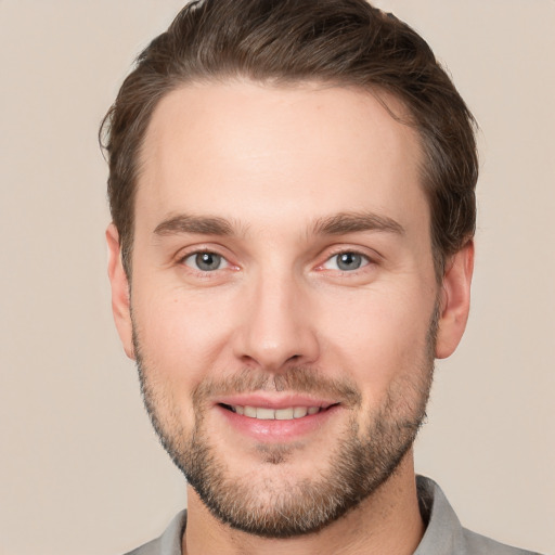 Joyful white young-adult male with short  brown hair and grey eyes