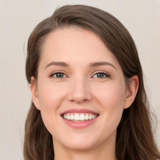 Joyful white young-adult female with long  brown hair and grey eyes