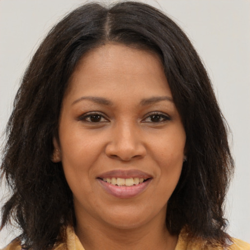 Joyful black young-adult female with long  brown hair and brown eyes