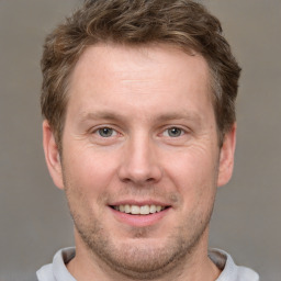 Joyful white adult male with short  brown hair and grey eyes