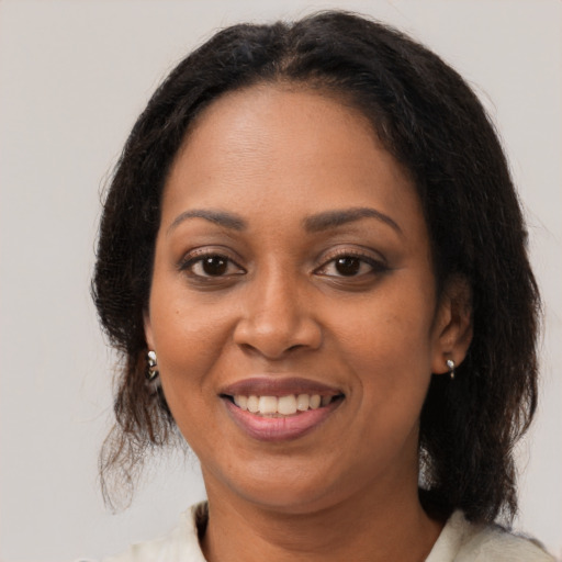 Joyful black adult female with medium  brown hair and brown eyes