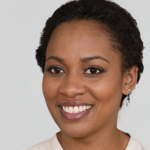 Joyful black young-adult female with short  brown hair and brown eyes