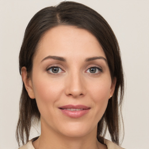 Joyful white young-adult female with medium  brown hair and grey eyes