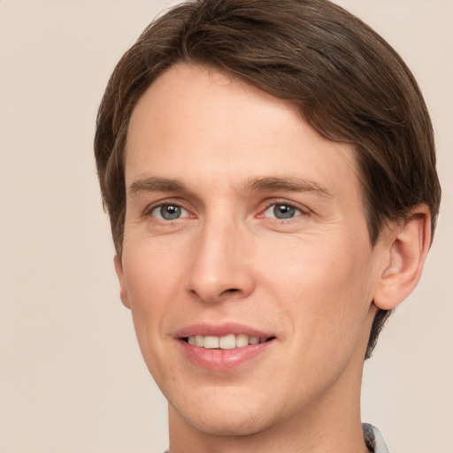 Joyful white young-adult male with short  brown hair and grey eyes