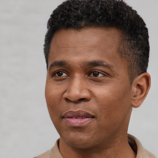 Joyful black young-adult male with short  brown hair and brown eyes
