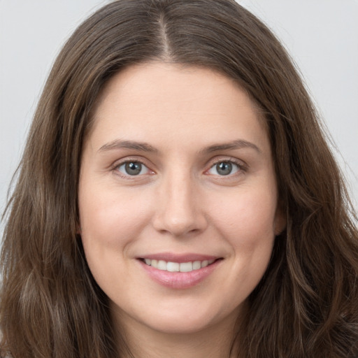 Joyful white young-adult female with long  brown hair and grey eyes