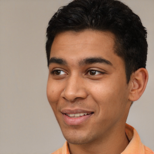 Joyful latino young-adult male with short  black hair and brown eyes