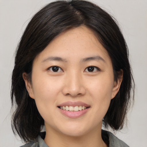 Joyful asian young-adult female with medium  brown hair and brown eyes