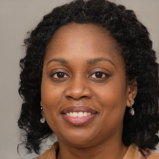 Joyful black young-adult female with long  brown hair and brown eyes