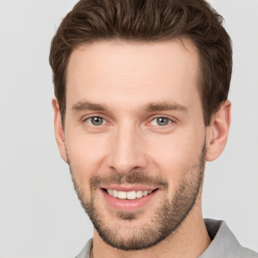 Joyful white young-adult male with short  brown hair and grey eyes