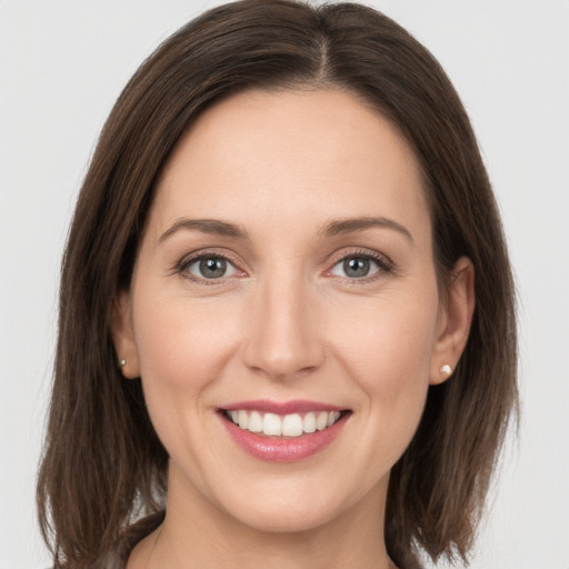 Joyful white young-adult female with medium  brown hair and grey eyes