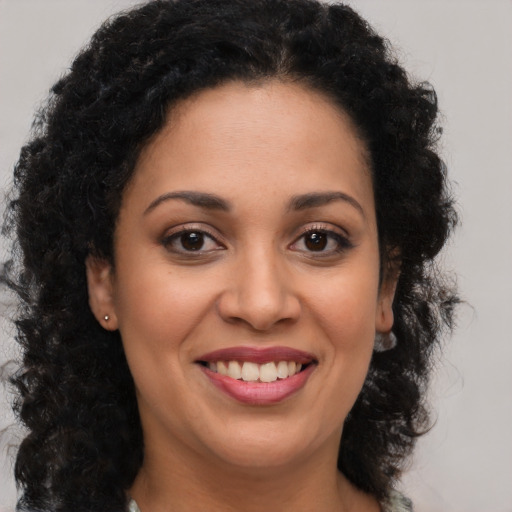 Joyful black young-adult female with long  brown hair and brown eyes