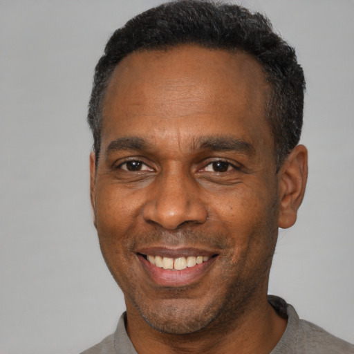 Joyful black adult male with short  black hair and brown eyes