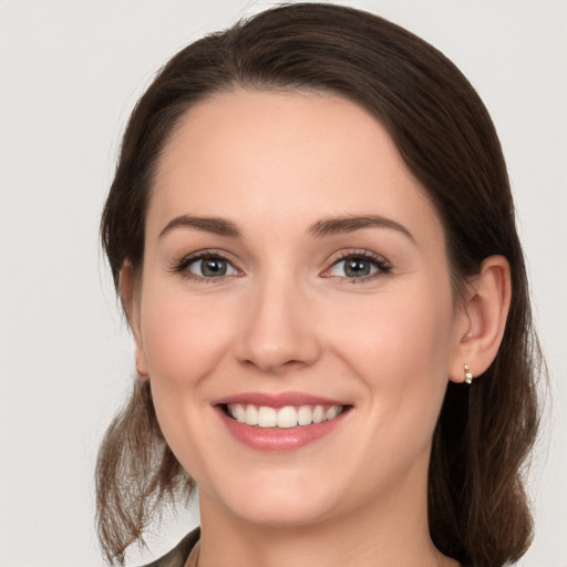 Joyful white young-adult female with medium  brown hair and grey eyes