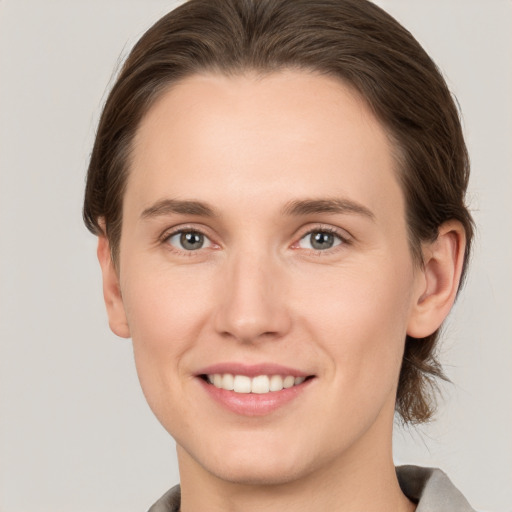 Joyful white young-adult female with medium  brown hair and grey eyes