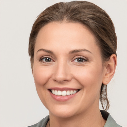 Joyful white young-adult female with medium  brown hair and grey eyes