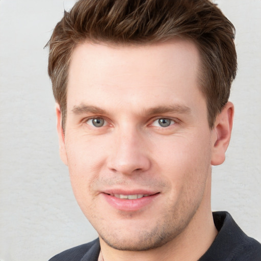 Joyful white young-adult male with short  brown hair and grey eyes