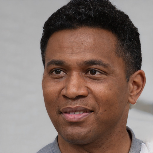 Joyful black adult male with short  black hair and brown eyes