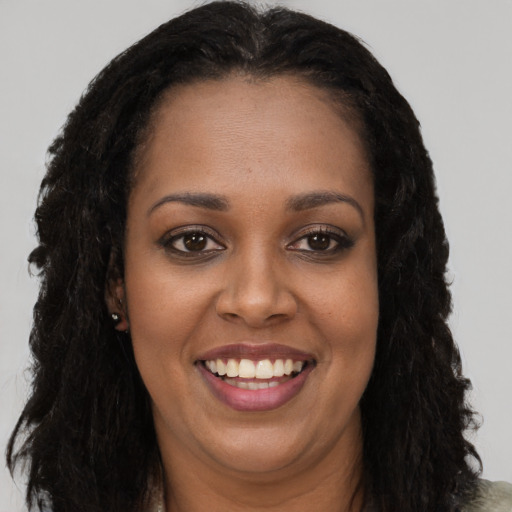 Joyful black young-adult female with long  brown hair and brown eyes