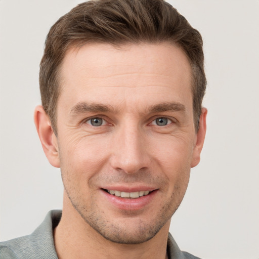 Joyful white young-adult male with short  brown hair and grey eyes