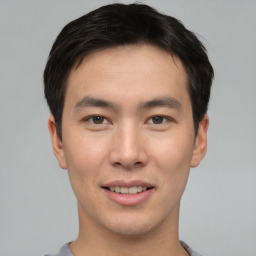 Joyful asian young-adult male with short  brown hair and brown eyes