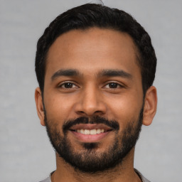 Joyful latino young-adult male with short  black hair and brown eyes