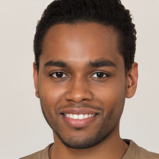 Joyful black young-adult male with short  brown hair and brown eyes