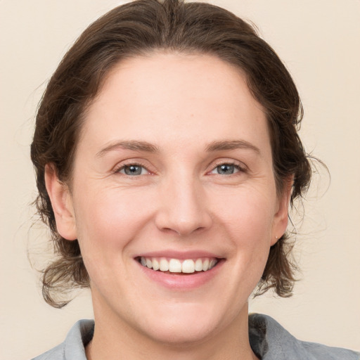 Joyful white young-adult female with medium  brown hair and grey eyes