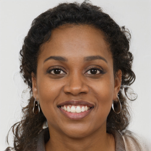 Joyful black young-adult female with long  brown hair and brown eyes